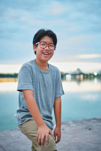 Portrait of teenage boy standing against sky