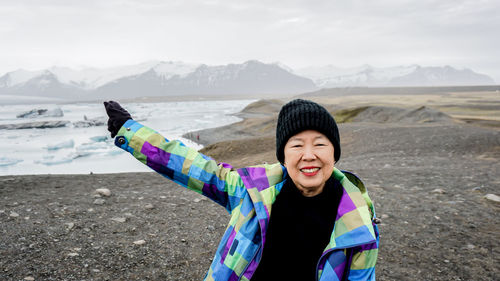Portrait of smiling woman standing by lake during winter