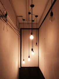 Low angle view of illuminated pendant lights hanging from ceiling