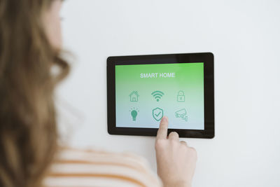 Close-up of woman using digital tablet with smart home app on the wall