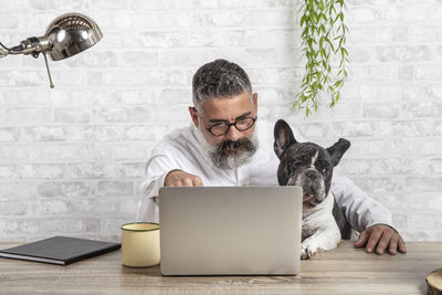 Freelance man working from home with his dog sitting together in office person