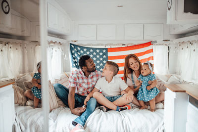 Full length of family sitting against american flag