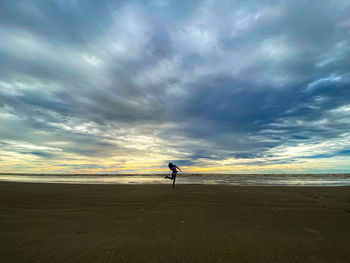 Man on beach against sky during sunset