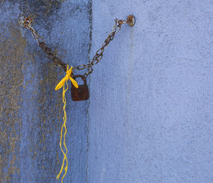 Close-up of padlock hanging on rope against wall