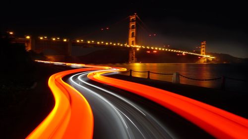 Light trails on bridge against sky at night