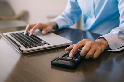 Midsection of man using laptop on table