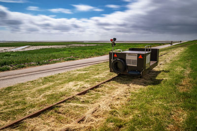 Railroad track amidst field against sky