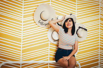 Young woman wearing hat against wall