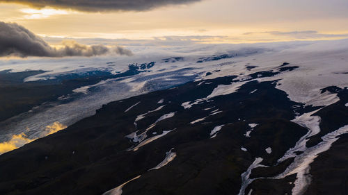 Aerial view of snowcapped mountains against sky during sunset