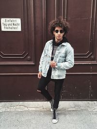 Portrait of young man standing against building