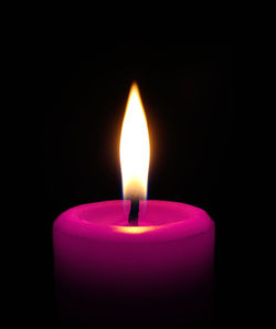 Close-up of lit candle on black background