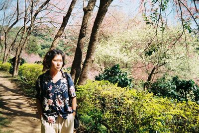 Portrait of young woman standing against trees