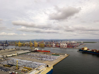 Aerial logistics commercial vehicles waiting to be load on to a car carrier ship at dockyard