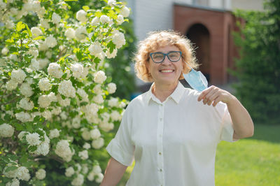 Portrait of smiling woman standing against white wall