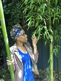 Portrait of young woman standing against plants