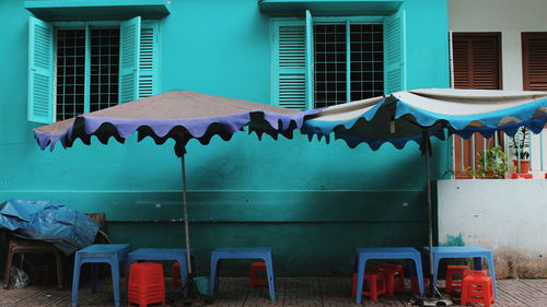 Empty chairs and tables against building
