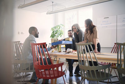 Male engineer showing architectural model to colleagues at table during meeting in office