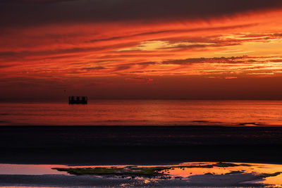 Scenic view of sea against dramatic sky during sunset
