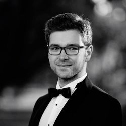 Portrait of smiling handsome man wearing suit standing outdoors