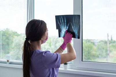 Side view of young woman using mobile phone at home