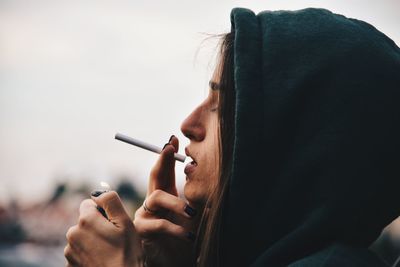 Close-up portrait of woman holding cigarette 