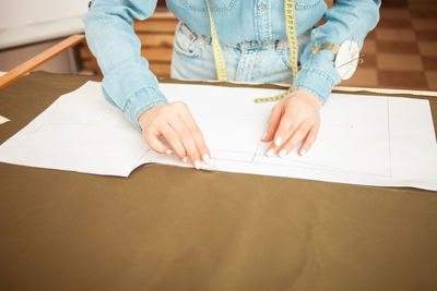 Midsection of woman writing in book