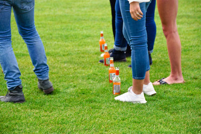 Low section of people with bottles standing on field