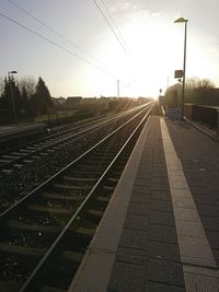 Railroad station platform against sky at sunset