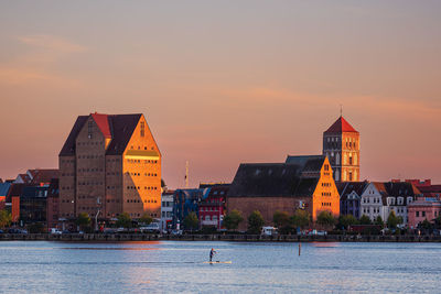 Buildings at waterfront during sunset