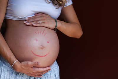 Midsection of woman touching face against black background