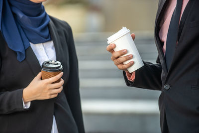 Midsection of woman holding ice cream standing outdoors