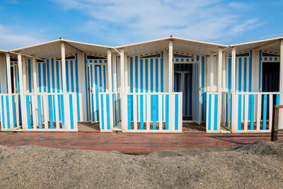 Striped white and blue striped beach houses and black sandy beach, tyrrhenian sea near roma, italy