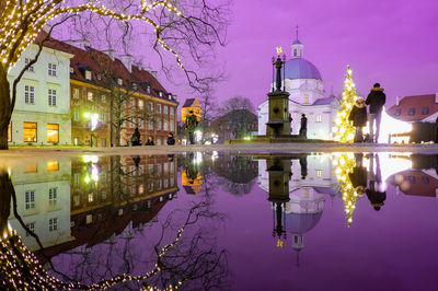 Reflection of buildings on puddle at night