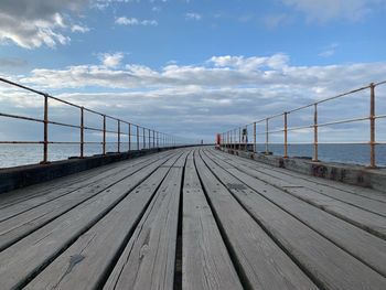 Surface level of pier over sea against sky