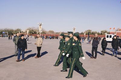 Army soldiers walking by crowd on street during sunny day