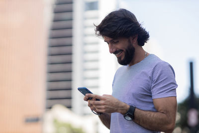 Young man with smartphone at night time with city view  in the background. mobile, technology, urban 