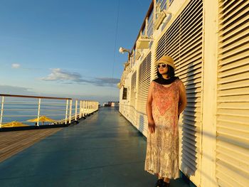 Woman standing by railing against sea