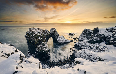 Seascape with snowy rocks and ocean during sundown