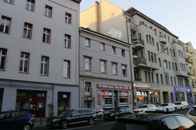 Cars on street by buildings against sky in city