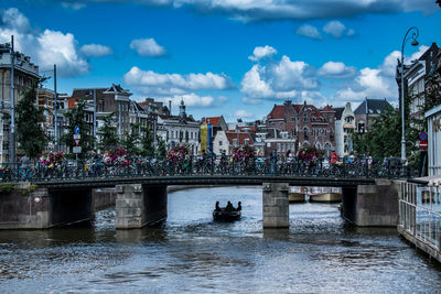 Bridge over canal amidst buildings in city against sky