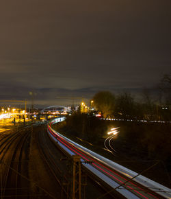 Light trails on road in city against sky at night