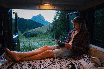 Young man reading book in motor home