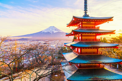 Temple in town against sky during sunset