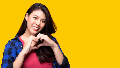 Portrait of a smiling young woman against yellow background