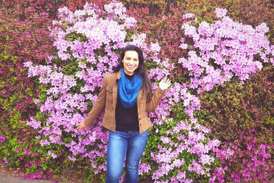 Portrait of smiling young woman standing against purple flowers