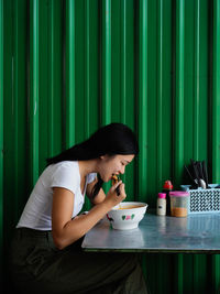 Side view of woman eating food while sitting at table