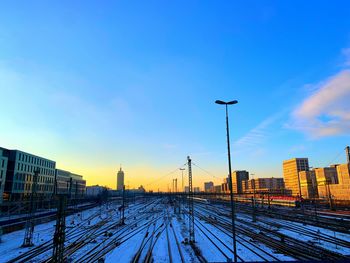 Railroad tracks by buildings against sky during winter