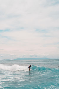 Man surfing in sea against sky