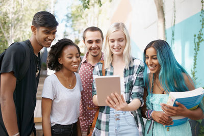 Cheerful friends using digital tablet