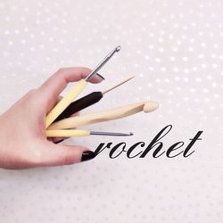 Cropped image of hand holding crochet hook against surface with text